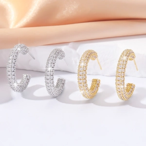 Detail of C-shaped pave cubic zirconia hoop earrings in gold and silver finish