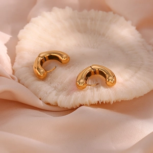 Macro detail of chunky gold plated stainless steel heart hoop earrings on coral tray