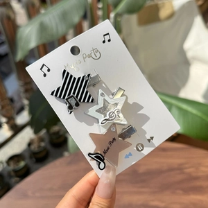 Detailed view of three acrylic star hair clips with music motifs on decorative card