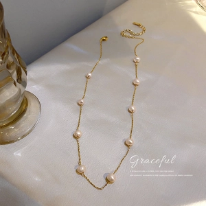 Elegant gold choker necklace featuring dainty freshwater pearls on a beige silk fabric