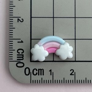 Macro shot of mini rainbow resin flatback with clouds showing size on scale mat