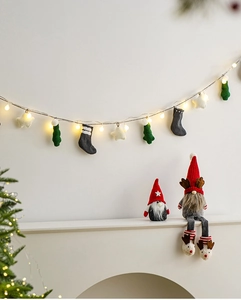 Close-up of lighted Christmas garland with warm LED stars, socks and plush gnomes