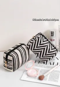 Detailaufnahme der schwarz-weißen Web-Kosmetiktasche mit goldenem Reißverschluss und Beauty