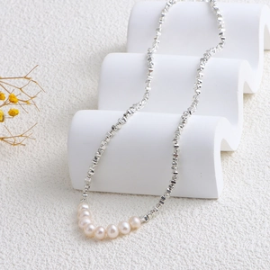 Macro shot of silver irregular geometric chain and eight white natural pearls on a stand