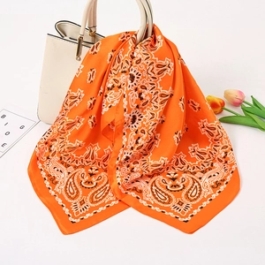 Leuchtend orangefarbenes Seidentuch mit Paisle mit Paisley-Muster an einer beigen Handtasche