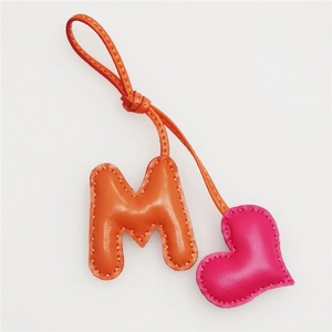 Detail of leather letter M and heart charm with fine white contrast stitching