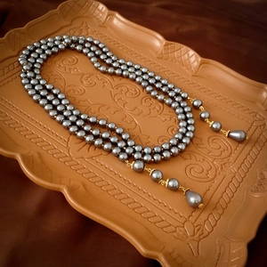 Close-up of multilayer grey pearl necklace with water drop pendants on vintage tray
