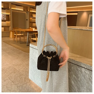 Detail of sparkly black drawstring bucket bag with gold ring handle and tassel charm