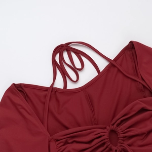 Détail d'une robe en tricot bordeaux avec anneau central en métal et tissu froncé