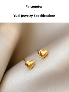 Macro detail of 3D heart stud earrings in 18K gold finish on elegant silk fabric