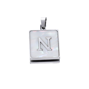 Close-up of square stainless steel pendant with white mother-of-pearl and letter N