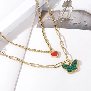 Detailed close-up of double layer gold necklace with red heart and green butterfly charms