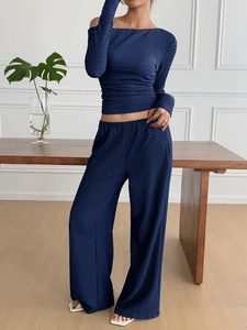 Detail of navy blue pleated lounge set featuring off-shoulder top and wide-leg pants