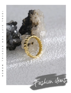 Close-up of golden gear-textured ring on stone surface for a minimalist vintage look