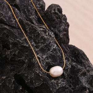 Minimalist 18K gold plated stainless steel necklace with a round white pearl on black rock
