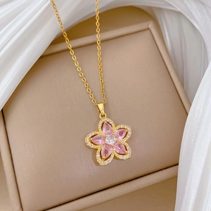 Macro detail of gold flower necklace with pink crystal petals in a jewelry box
