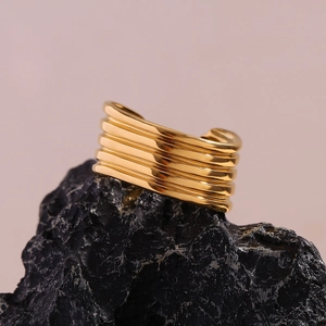 Vue macro d'une bague multi-rangs plaquée or 18 carats sur une roche noire texturée