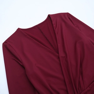 Nahaufnahme des tiefen V-Ausschnitts und der feinen Nähte an einem weinroten Kleid