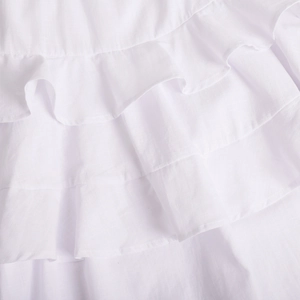 Detail of layered ruffle tiers on a white cotton summer dress with textured fabric
