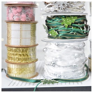 Close-up of glittery pink bows, green Christmas ribbons and white pearl beads strands