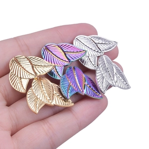 Close-up of four leaf-shaped stainless steel earrings in gold, silver, and rainbow finishes