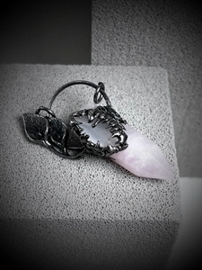 Detailed macro view of pink crystal hexagonal pillar held by gothic antique silver dragon claw