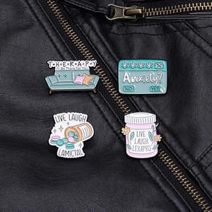 Detailed close-up of four colorful enamel lapel pins on a textured black leather jacket