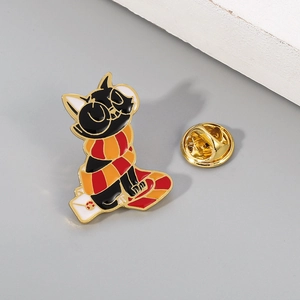 Detail of a black enamel cat pin wearing a red scarf with a golden butterfly clutch