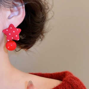 Detail of red fabric star earring with white polka dots and spherical bead on model