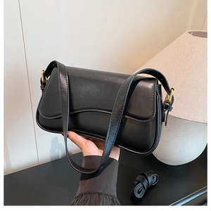 Detail of a black glossy leather shoulder bag with an adjustable golden metal buckle