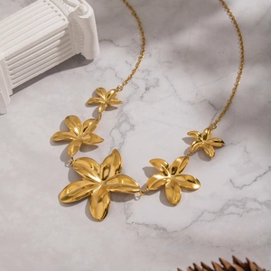 Detail view of a gold flower pendant necklace on an elegant marble surface background