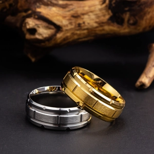 Close-up of gold and silver brushed titanium steel rings on dark stone with wood