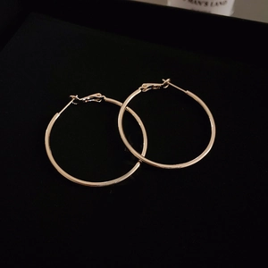 Close-up of elegant gold hoop earrings with smooth metallic texture on black background