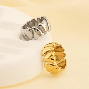Close-up of heart-shaped hollow rings in gold and silver finish on a wave texture base