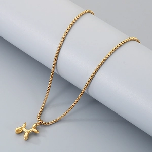 Détail du collier avec pendentif chien ballon doré sur une chaîne à maillons carrés