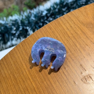Close-up of lavender marble acetate claw clip with 'Barrette La France' text on wood