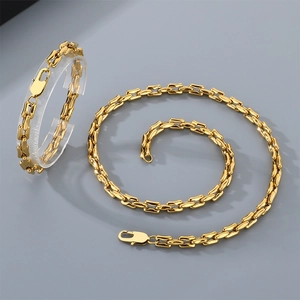 Detailansicht der 18k vergoldeten Gliederkette und des Armbands auf grauem Grund