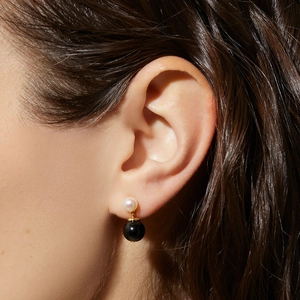 Detailed close-up of a two-tier gold earring with white pearl and large black onyx bead