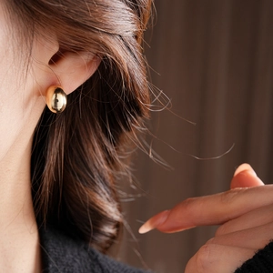 Close-up of elegant gold droplet earring worn by a model in soft ambient light