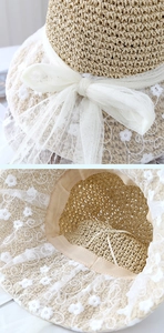 Detail of beige straw hat featuring delicate white lace petals and mesh bow decoration