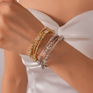 Detail of layered gold and silver bracelets with sparkling crystals on a model's wrist