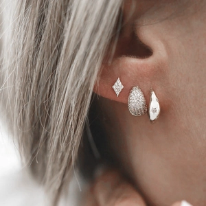 Close-up of S925 silver cross star hoop earrings with zircon pavé on a model ear