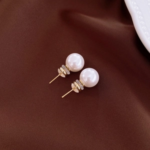 Macro detail of elegant round pearl stud earrings with polished golden metallic pins