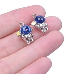 Detailed close-up of two silver astronaut pendants with blue glitter helmets and gold stars