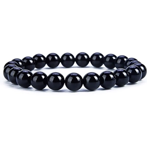 Macro shot of polished black agate beads on an elastic bracelet with reflective finish