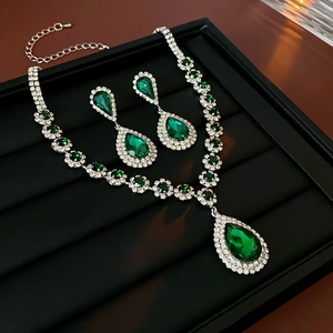 Dettaglio di set collana e orecchini in argento con pietre verdi a goccia e strass lucidi