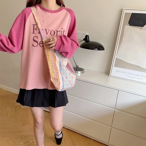 Pink and magenta raglan sleeve top paired with a black pleated skirt and patterned crossbody bag