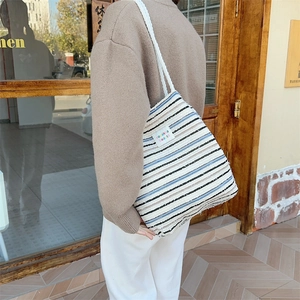 Detail of canvas tote bag showing striped fabric and thick white rope handles on shoulder