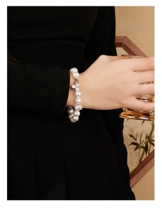Detail of silver clover pearl bracelet with small butterfly charms worn on wrist