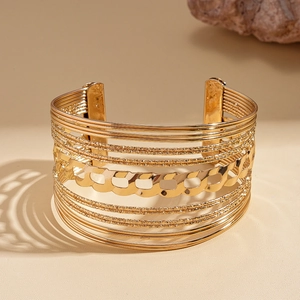 Close-up of golden multi-layer hollow geometric bangle with chain detail and matte texture
